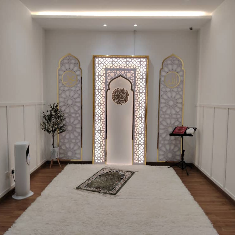 A prayer room with a prayer mat, wall decorations, and a rug.